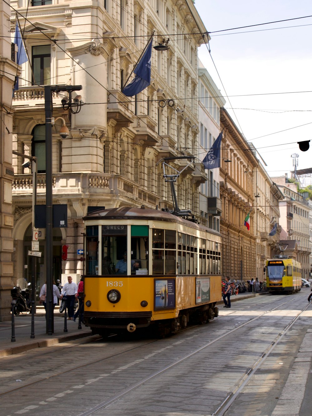 a yellow trolley is going down the street