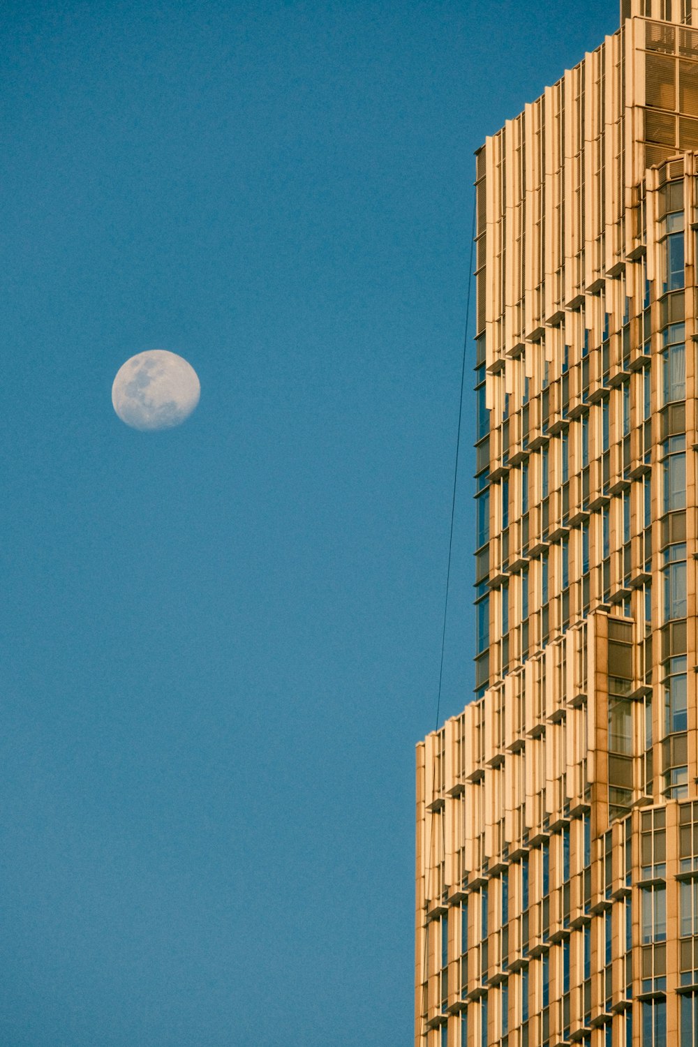 a very tall building with a half moon in the sky