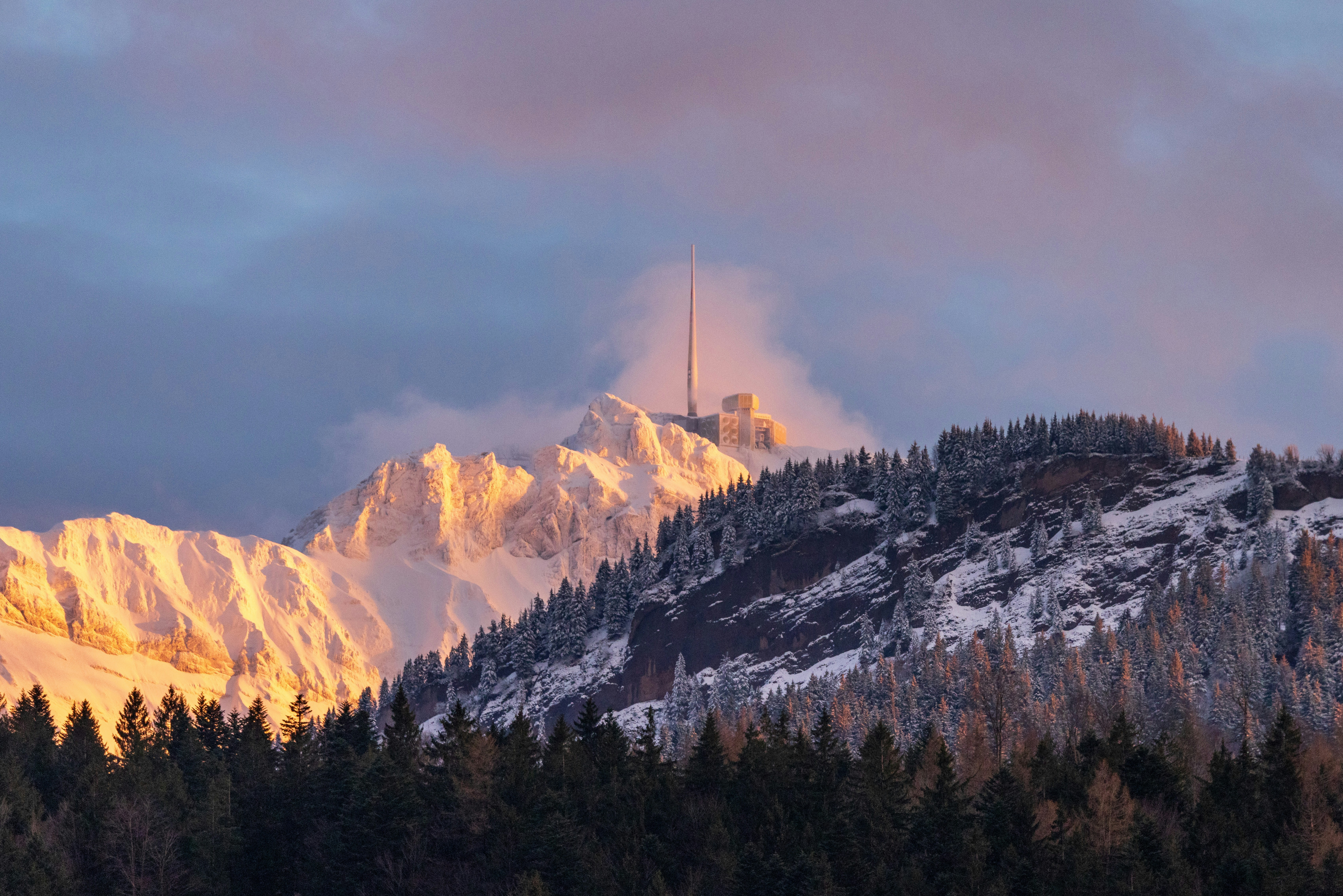 a mountain covered in snow with a radio tower on top of it