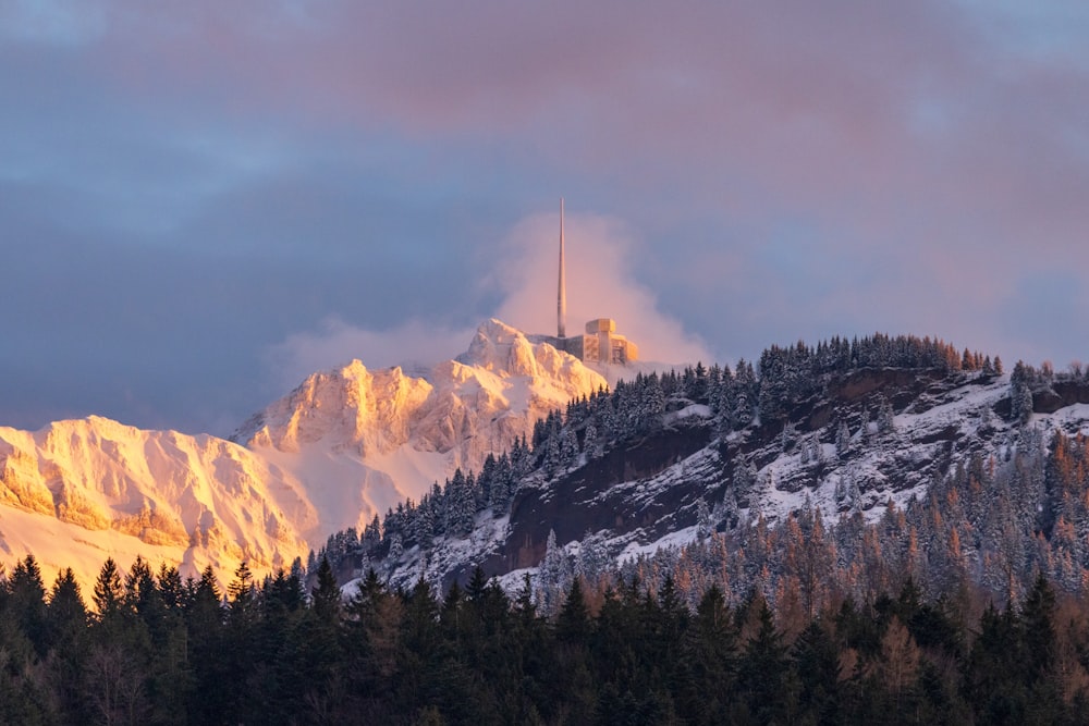 una montaña cubierta de nieve con una torre de radio en la cima
