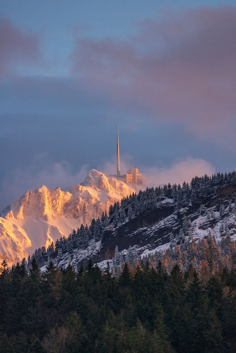 a mountain covered in snow with a radio tower in the distance