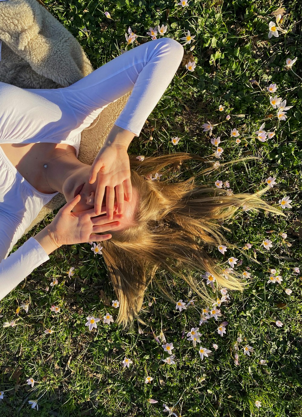 a woman laying in the grass with her hands on her head
