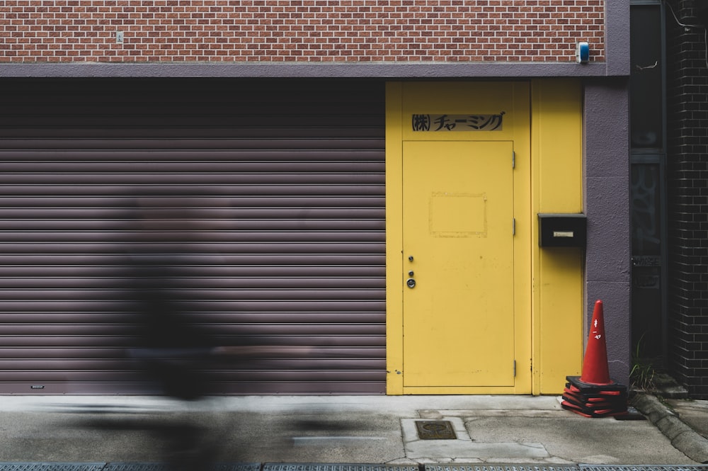 a person riding a bike past a yellow door