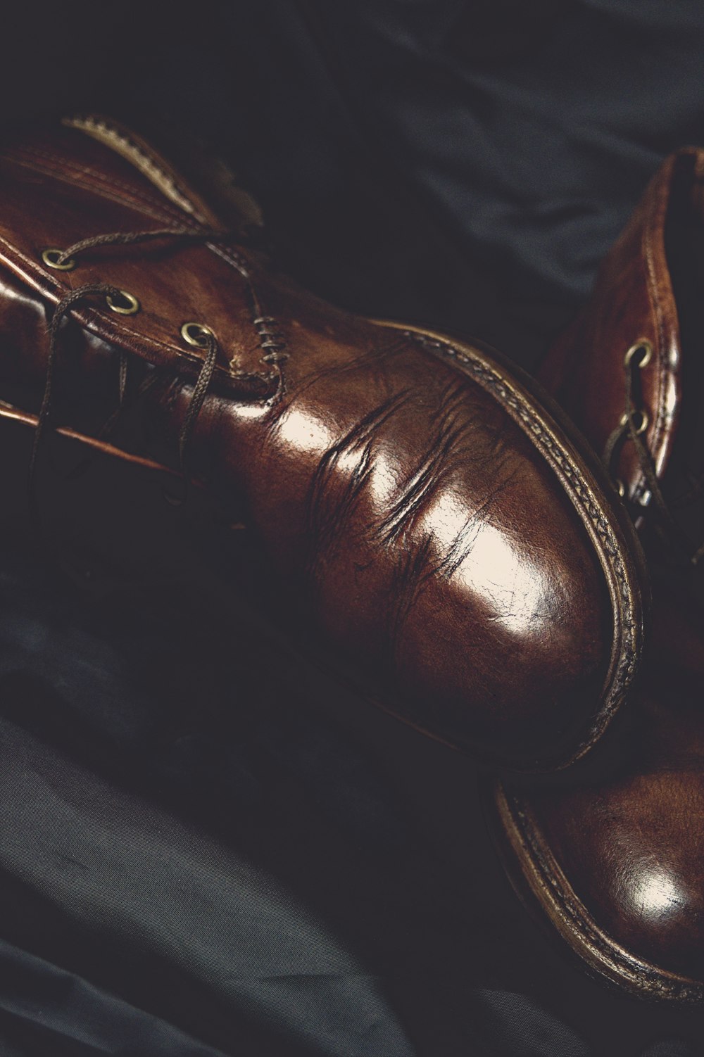 a pair of brown shoes sitting on top of a black cloth