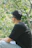 a man sitting on top of a wooden bench next to a forest