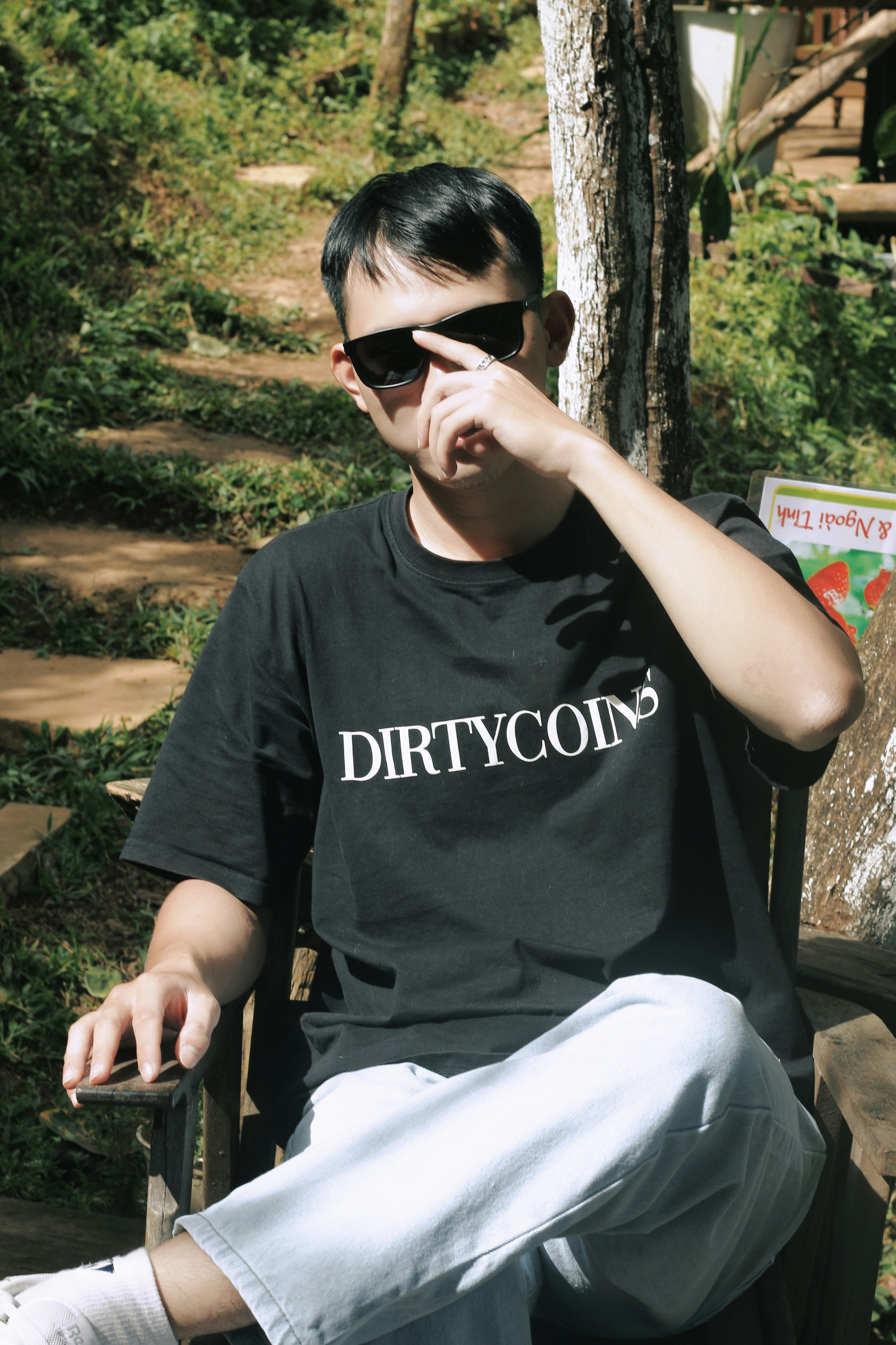 a man sitting on a wooden bench wearing sunglasses