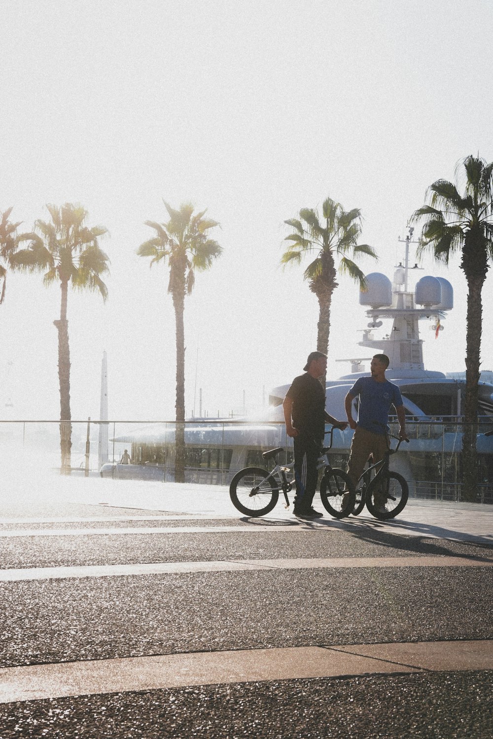 two men standing next to a motorcycle on a street