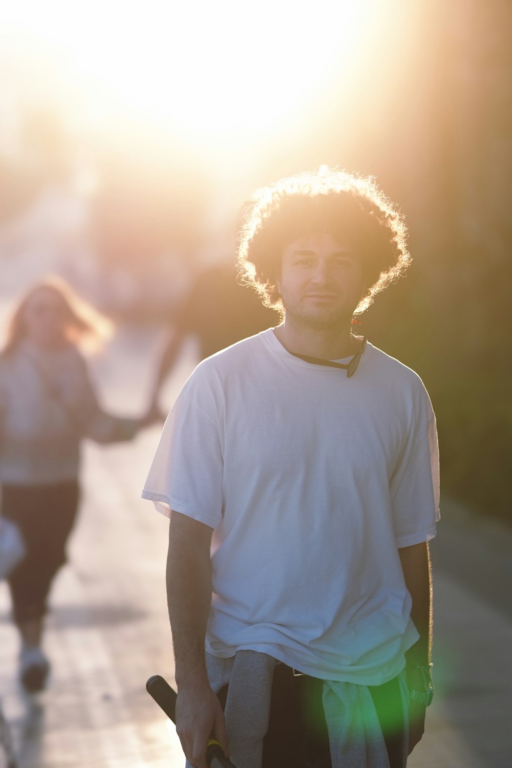 a man holding a skateboard while walking down a sidewalk