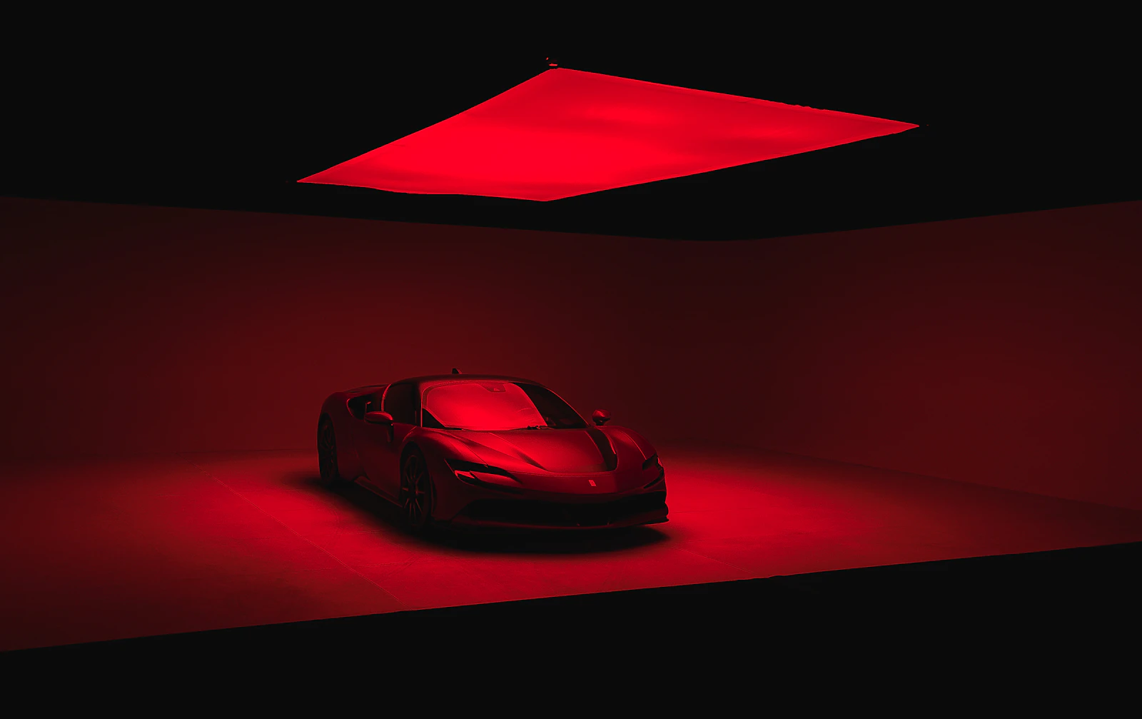 Red Ferrari lit by a single red light in a dark studio
