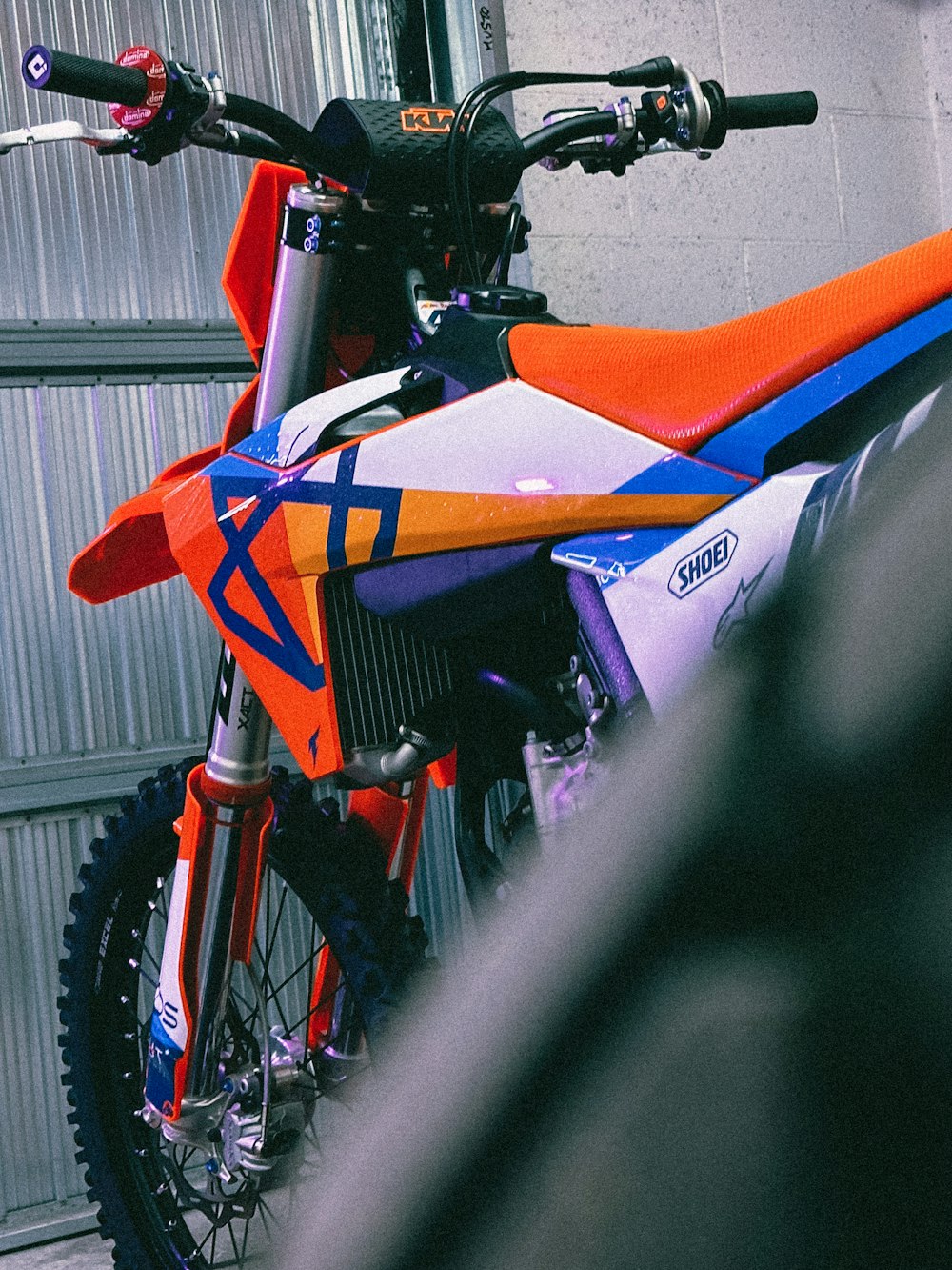 an orange and blue dirt bike parked in a garage