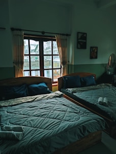 a couple of beds sitting in a bedroom next to a window