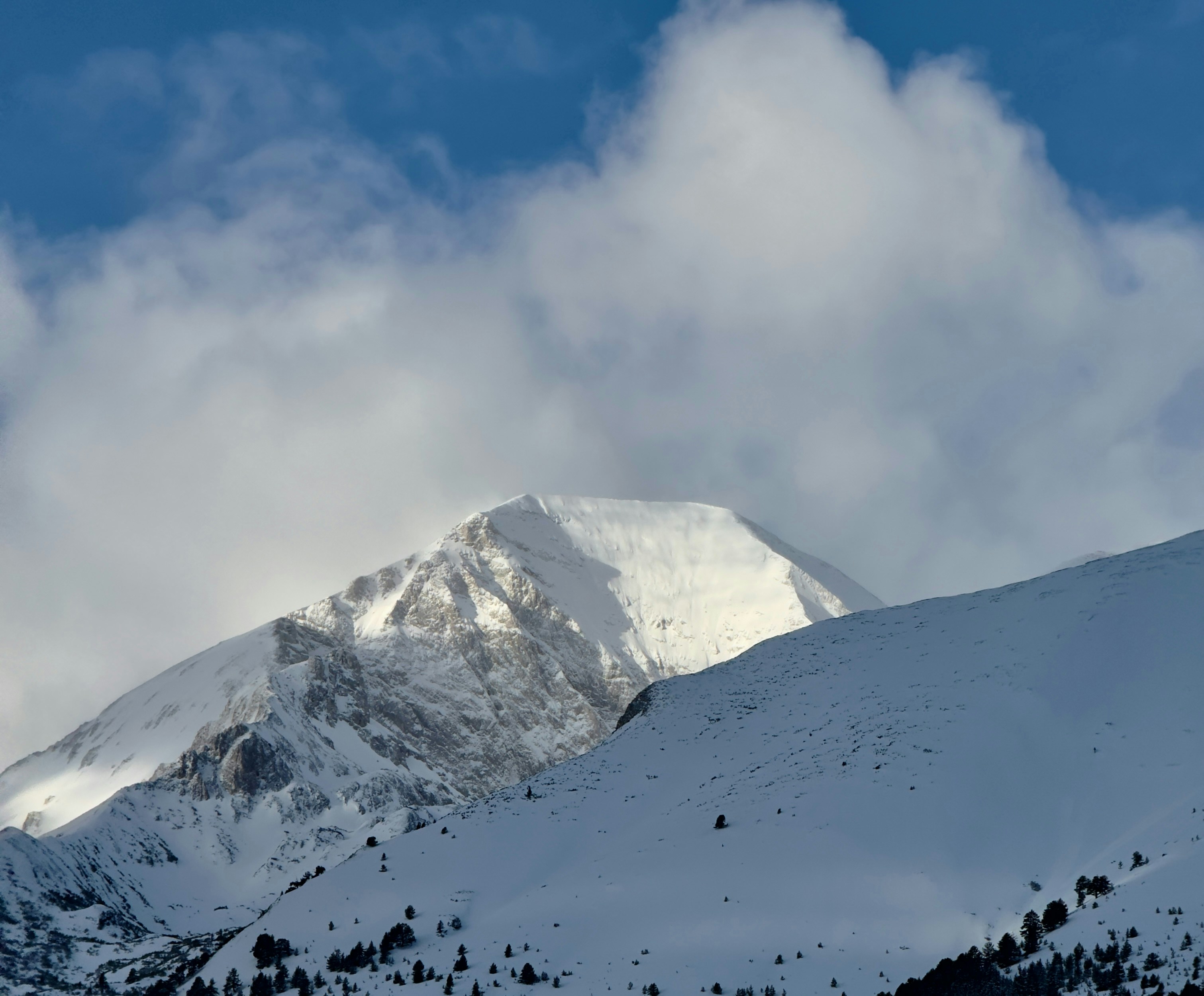 a mountain covered in snow under a cloudy sky, 