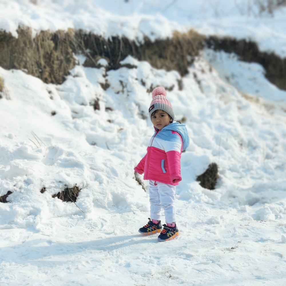 a little girl standing in the snow on skis