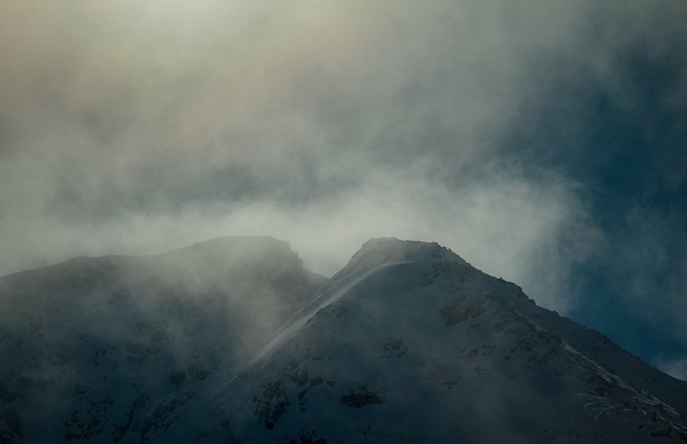 a snow covered mountain under a cloudy sky