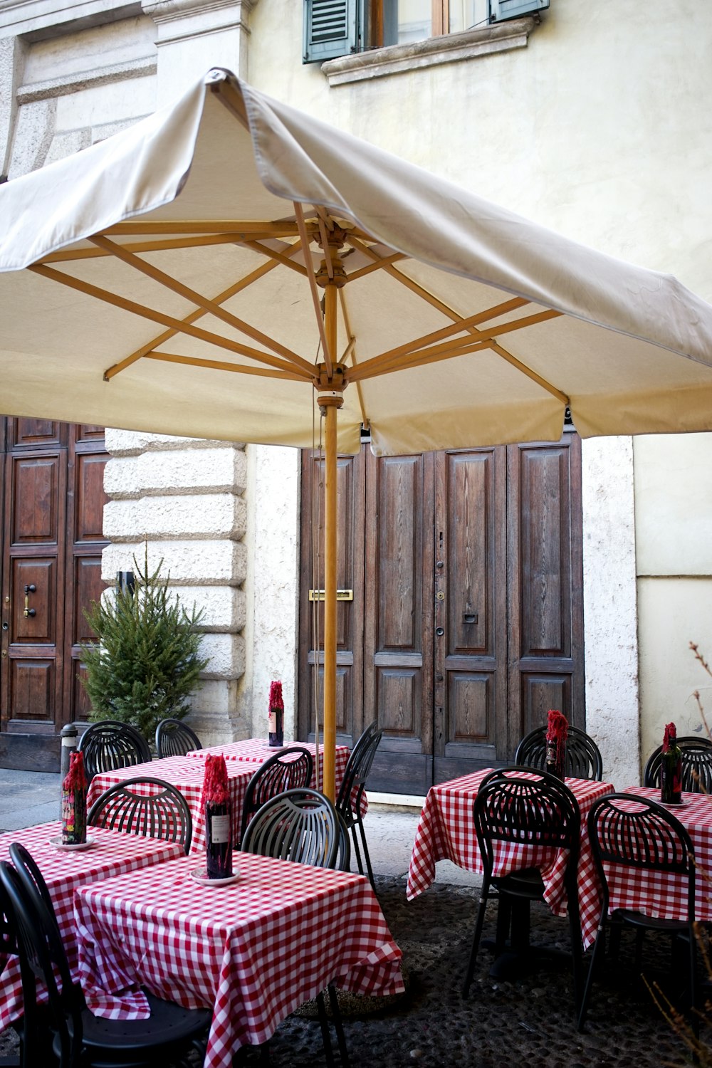 우산 아래에 빨간색과 흰색 체크 무늬 식탁보가 있는 테이블