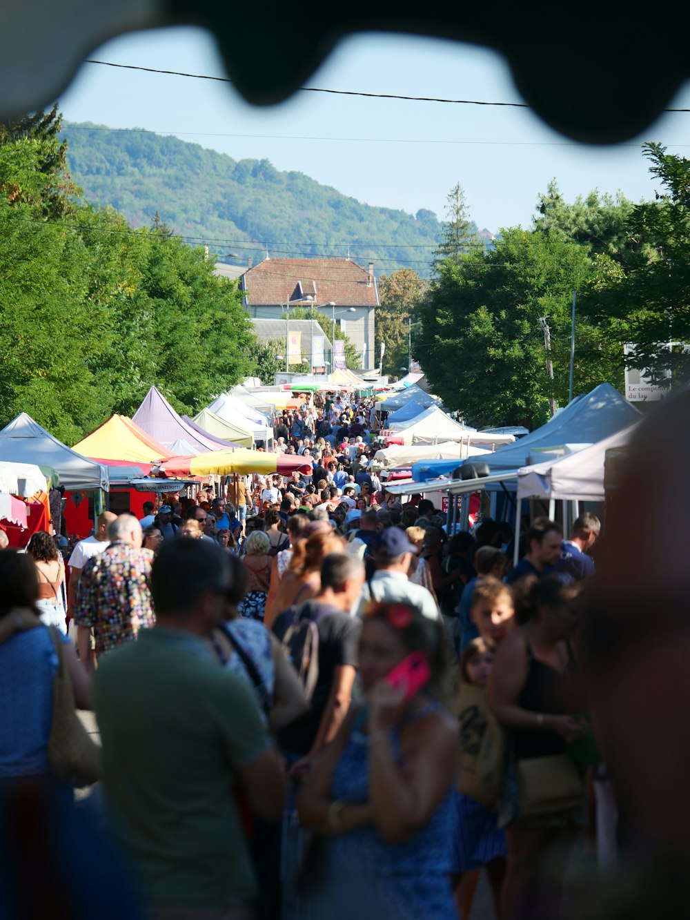 a crowd of people walking down a street next to tents