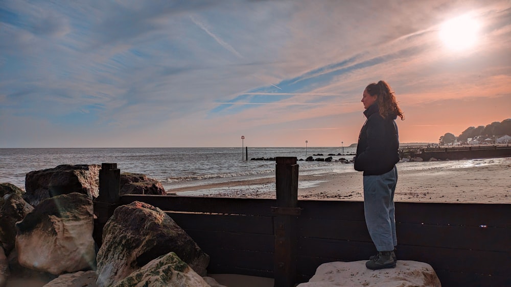 una donna in piedi su una roccia che guarda l'oceano