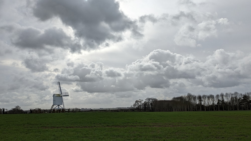 a windmill in a green field under a cloudy sky