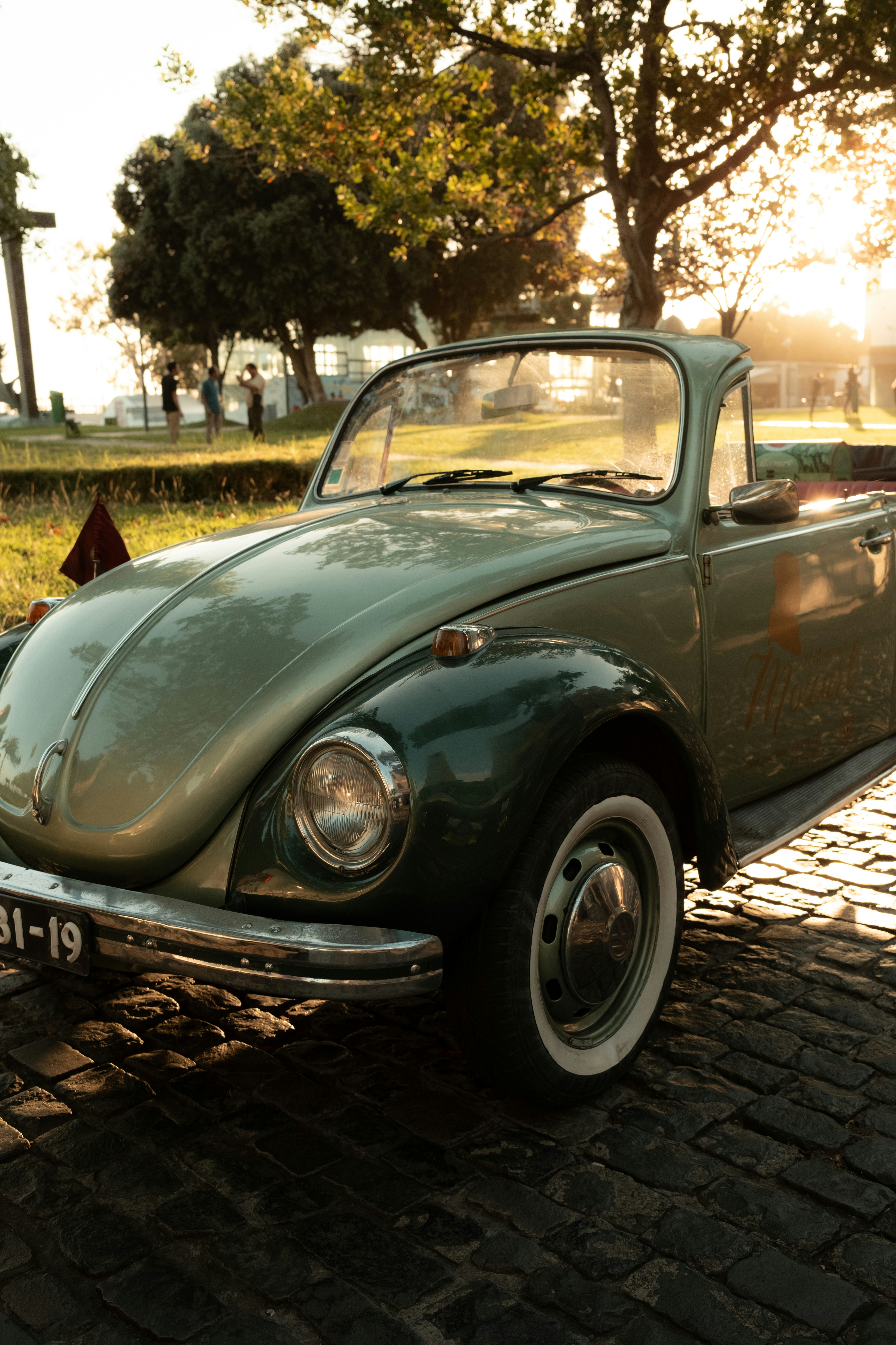 um carro verde estacionado em uma estrada de tijolos