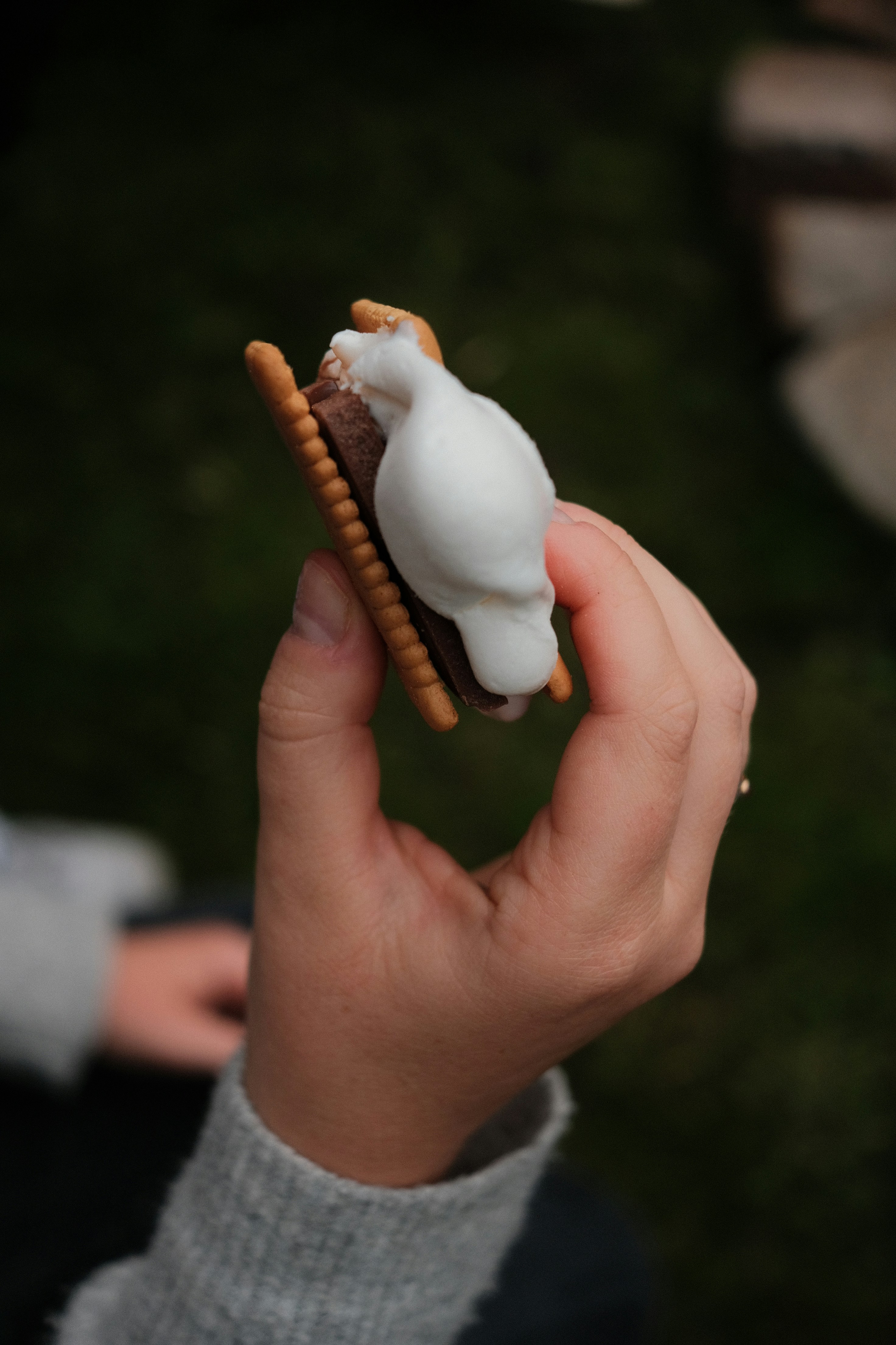 a person holding a small pastry with icing on it