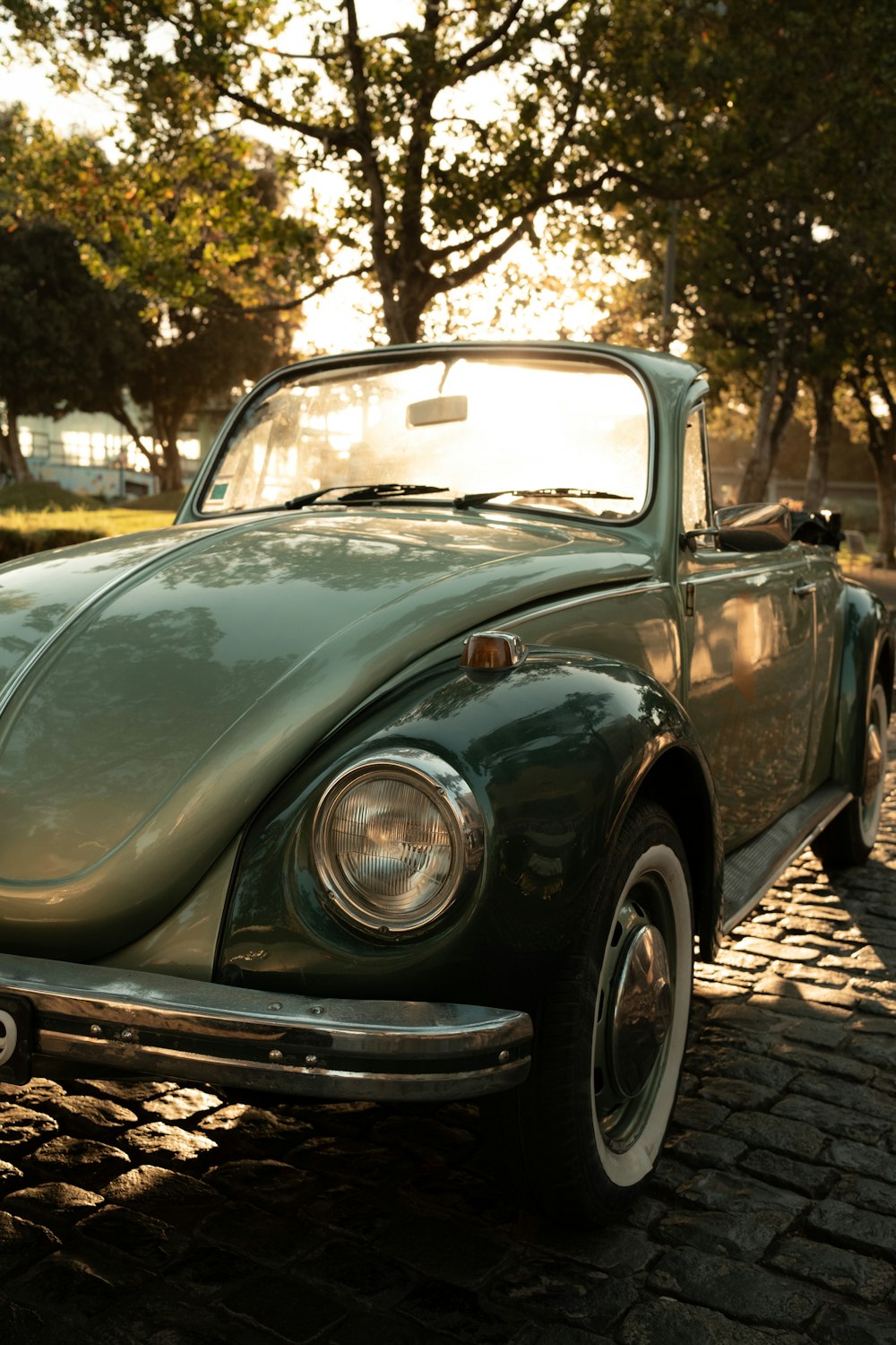 a green car parked on a cobblestone road