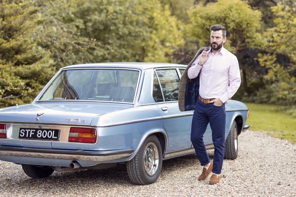 a man standing next to a blue car