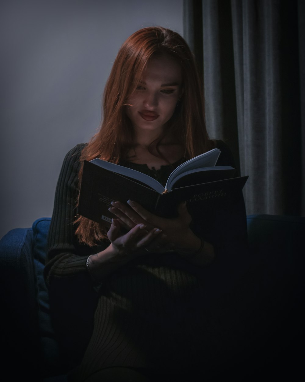 a woman sitting on a couch reading a book