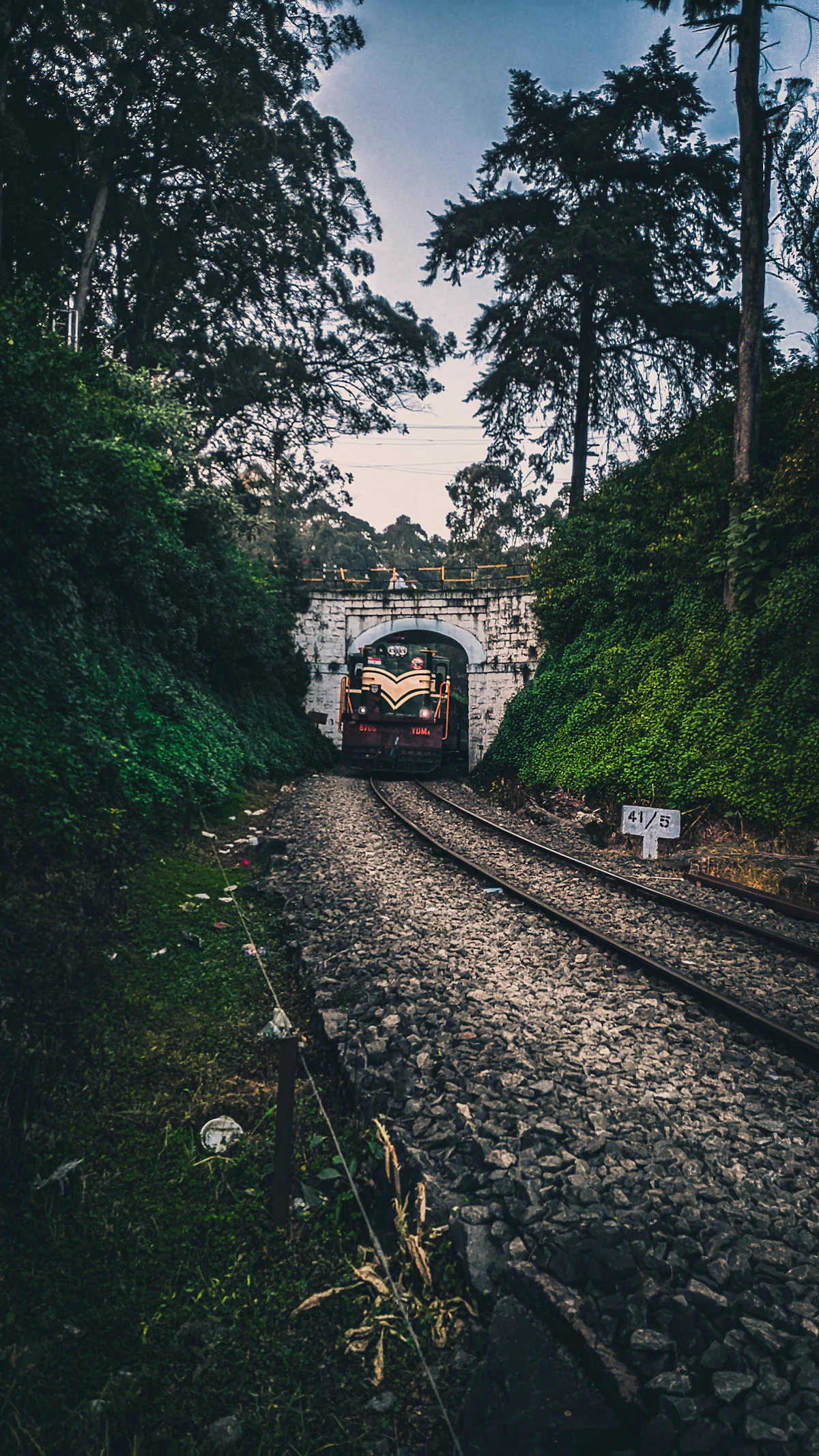 A railway tunnel portal with tracks running into the darkness