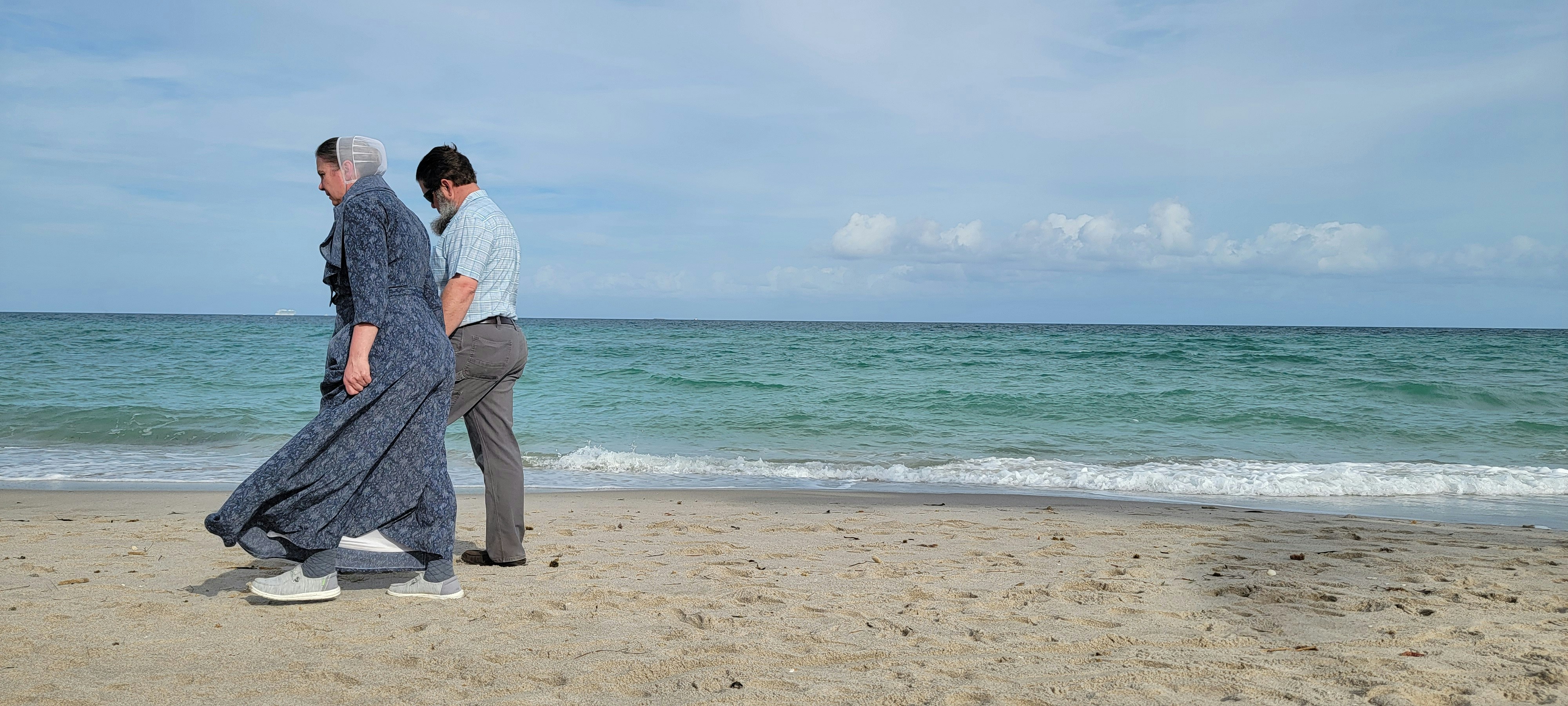 a couple of people standing on top of a sandy beach