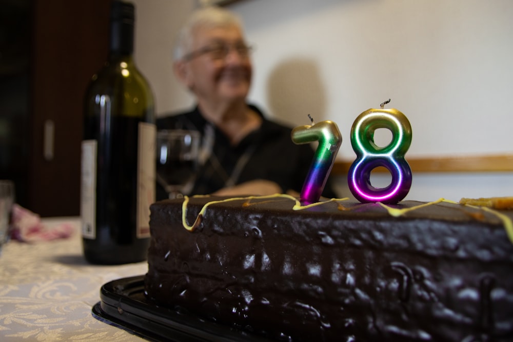 Un uomo seduto davanti a una torta al cioccolato con il numero ottanta