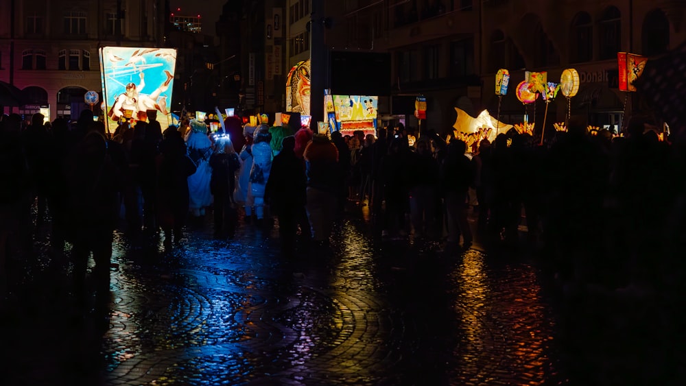 a crowd of people standing on a street at night