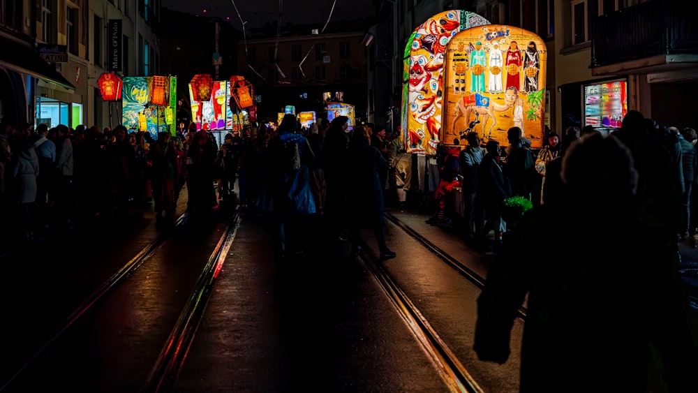 a crowd of people walking down a street at night