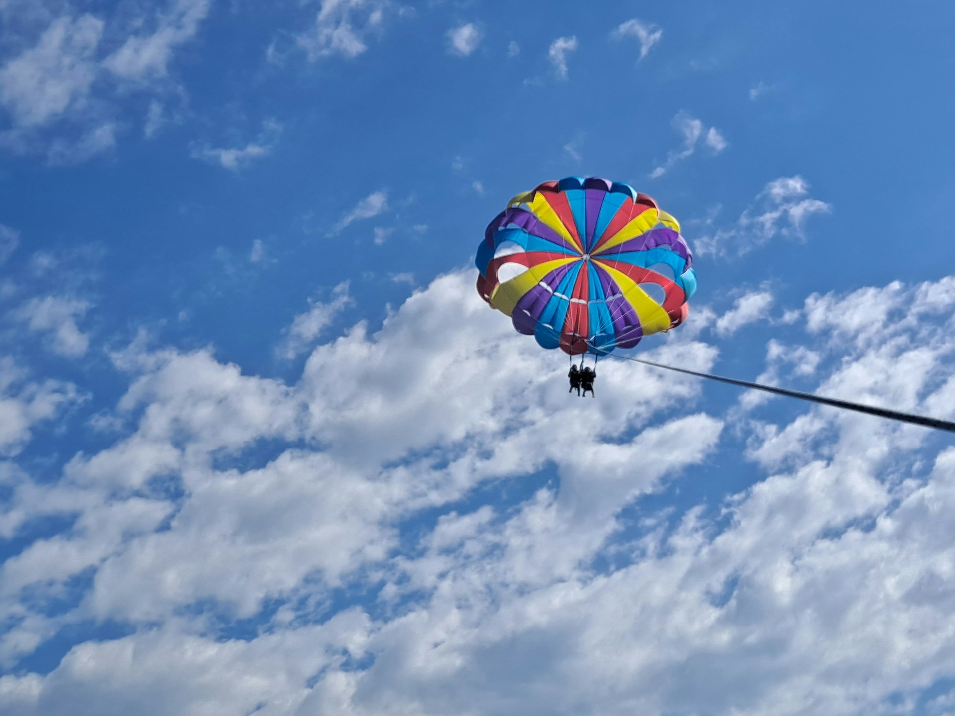 a colorful kite flying through a cloudy blue sky