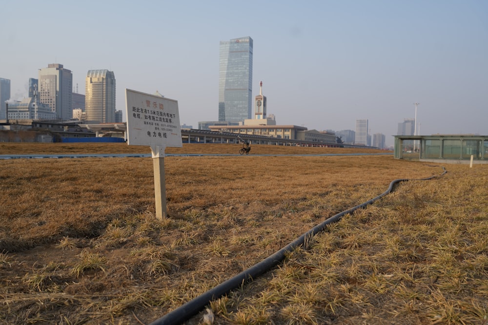 a sign in a field with a city in the background