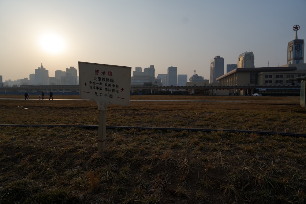 a sign in a field with a city in the background