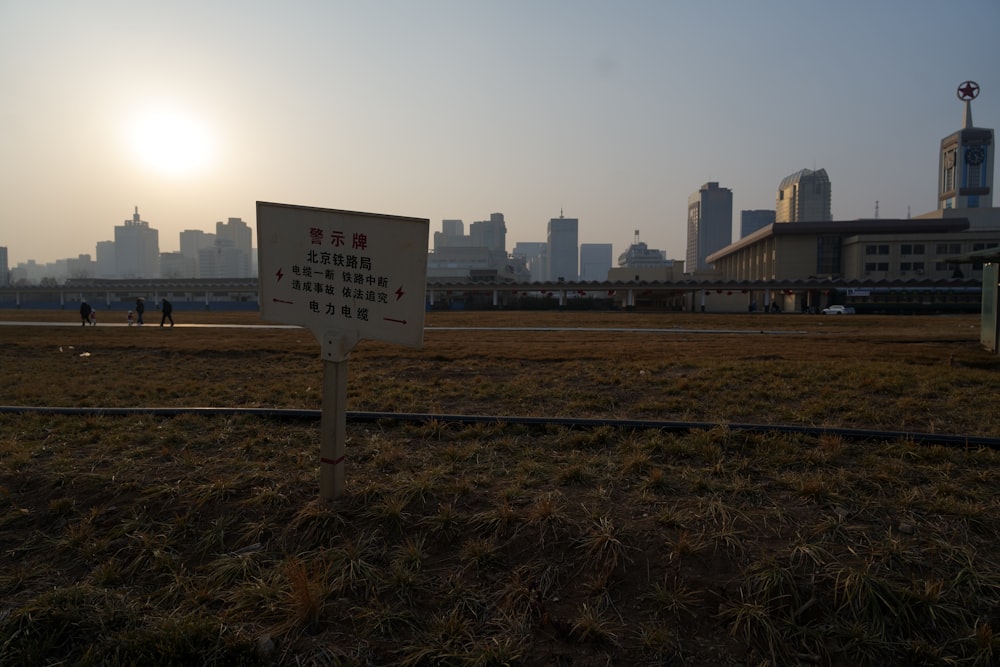 ein Schild auf einem Feld mit einer Stadt im Hintergrund