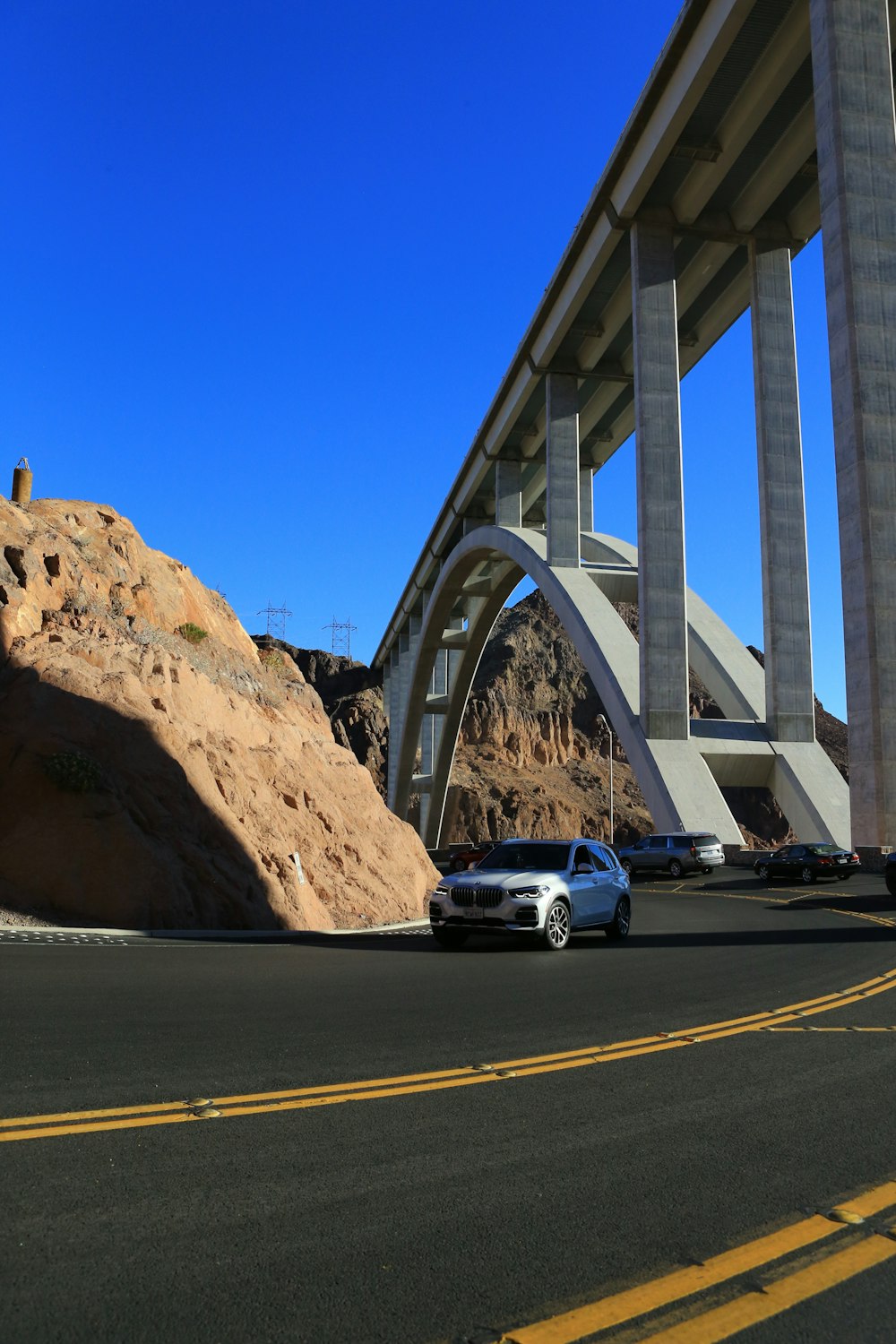 a white car driving down a road under a bridge