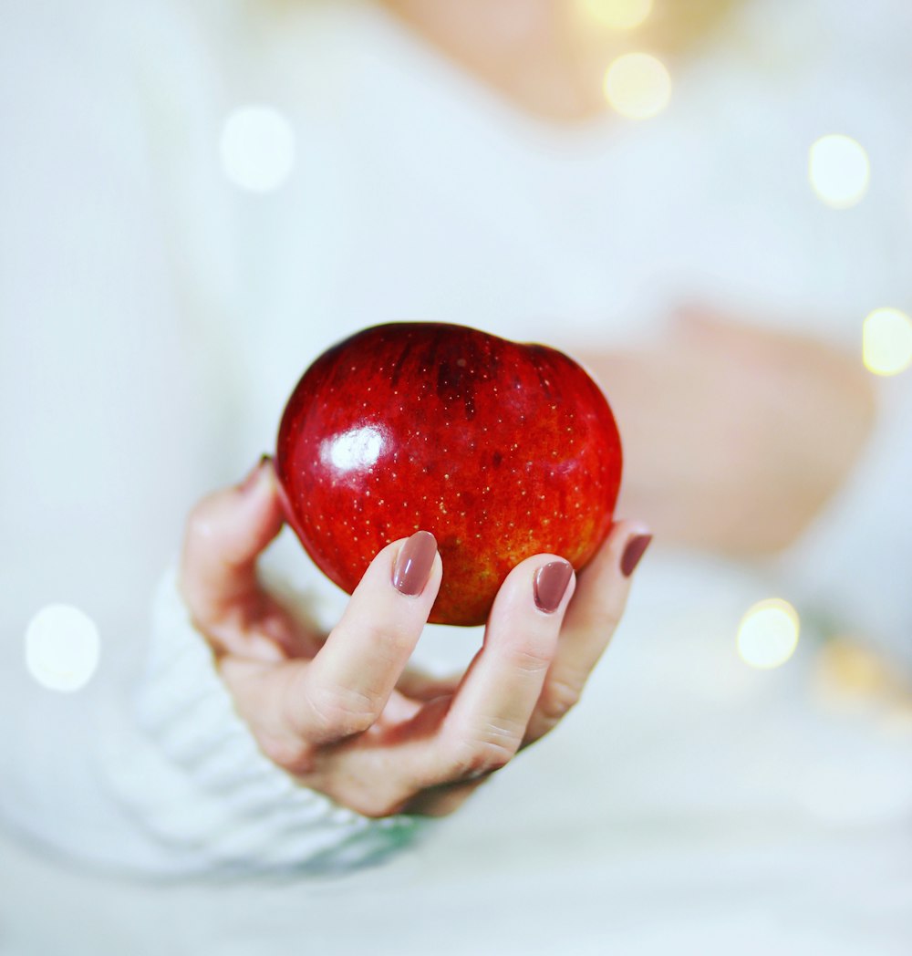 una mujer sosteniendo una manzana roja en sus manos