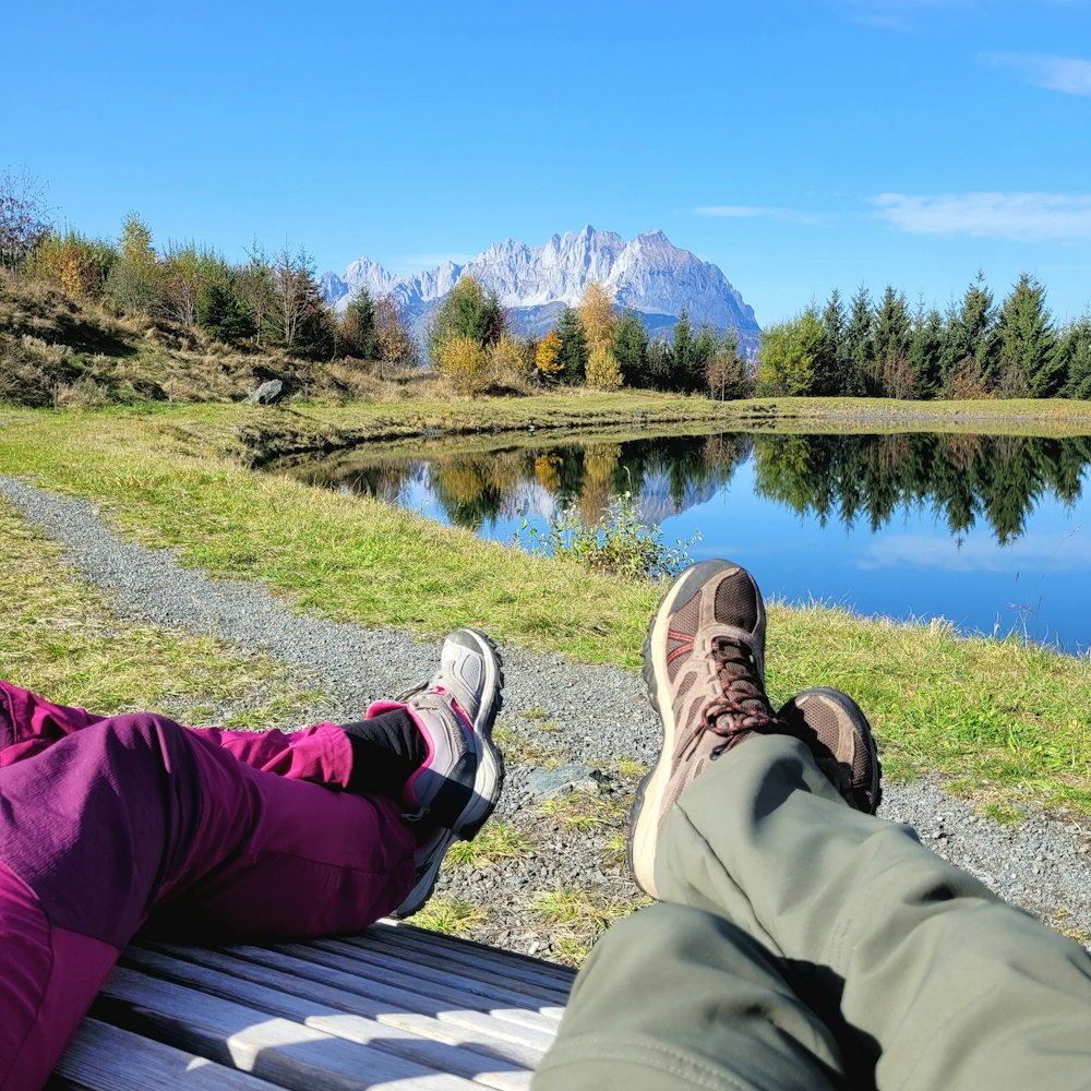 a couple of people sitting on a bench next to a lake