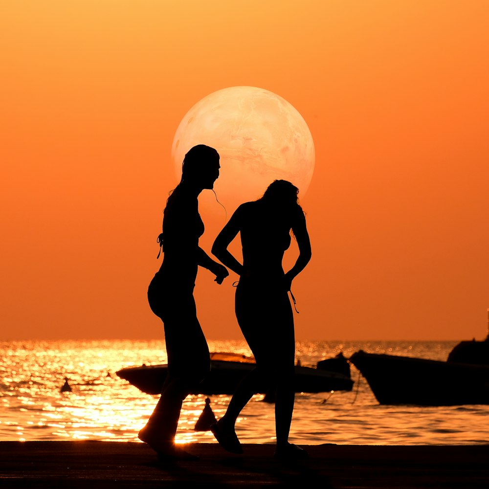 a couple of women standing next to each other on a beach