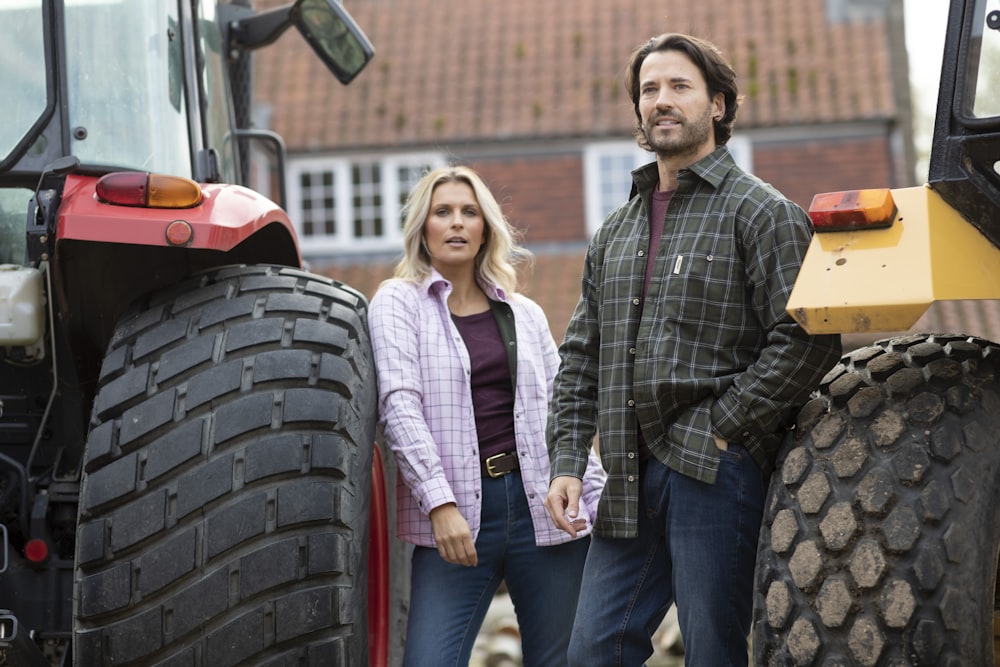 a man and a woman standing next to a tractor