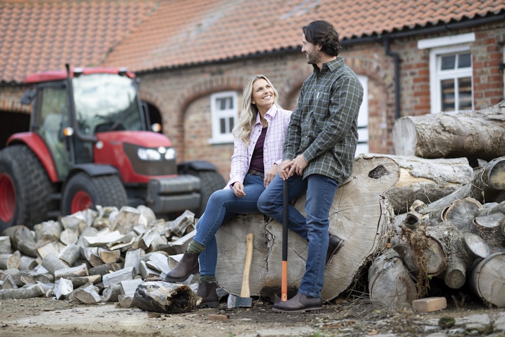 a man and a woman sitting on a pile of wood