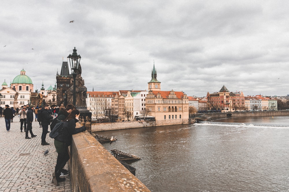 a group of people standing on a bridge next to a body of water