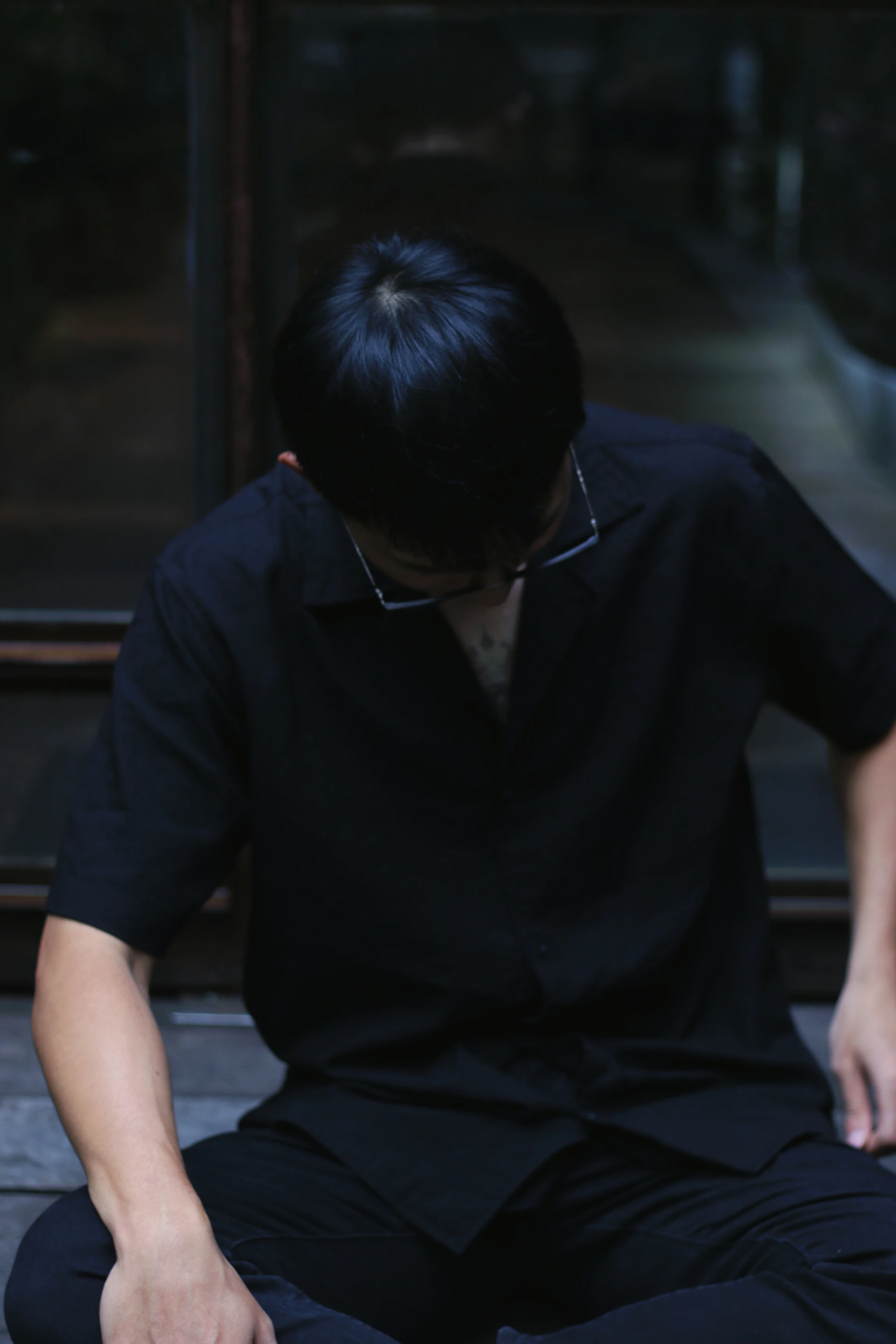 a man sitting on the ground with his hands in his pockets