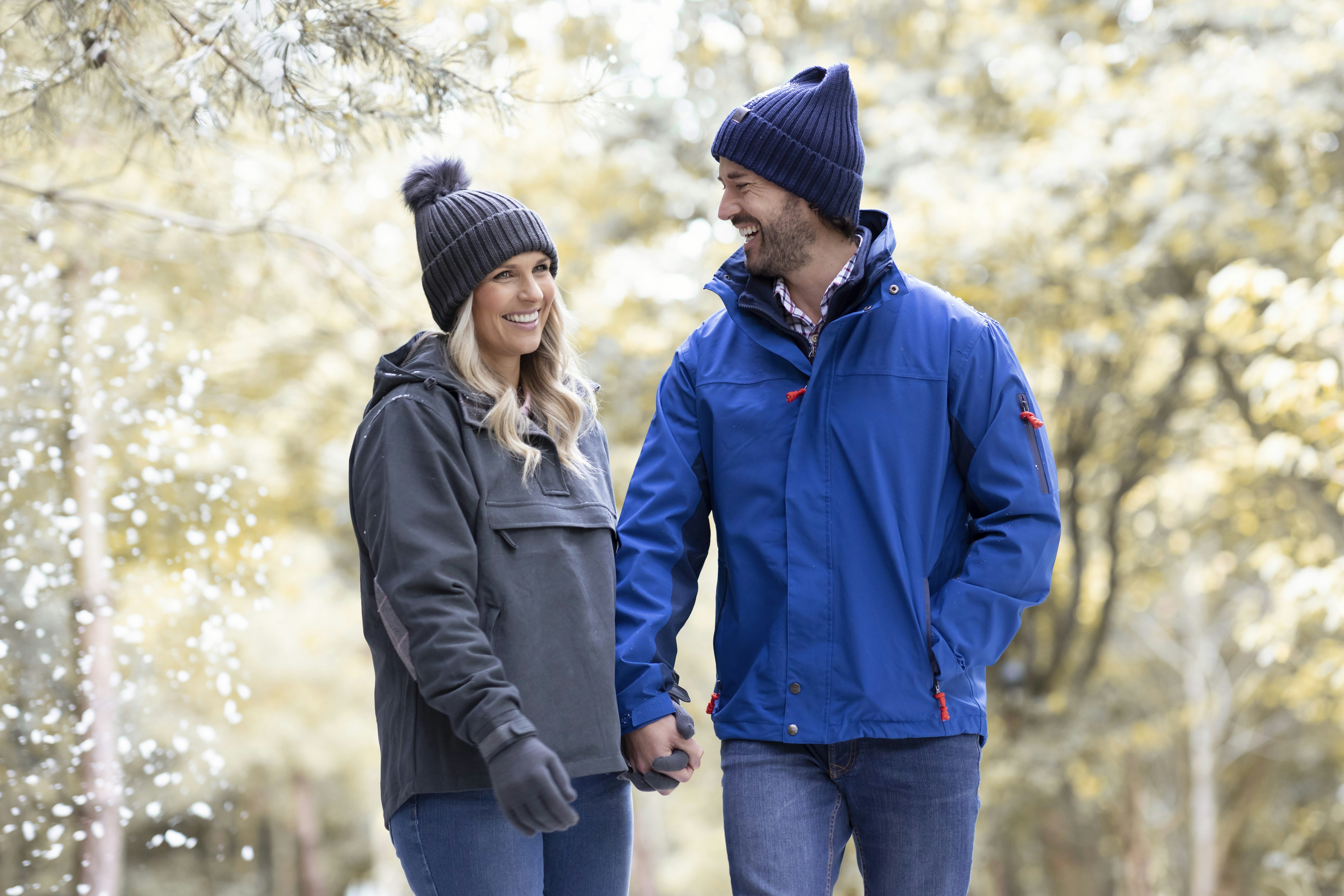 a man and a woman walking through a park holding hands