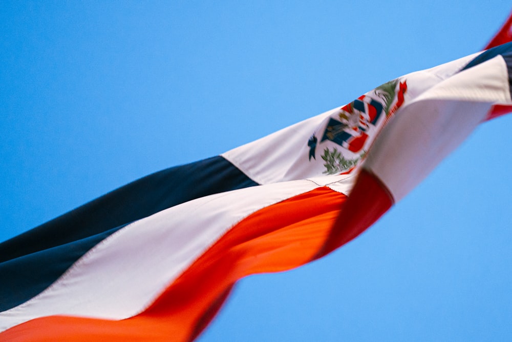 a flag flying in the wind with a blue sky in the background