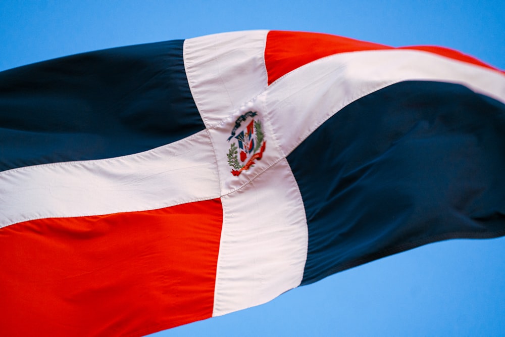 a flag flying in the wind with a blue sky in the background