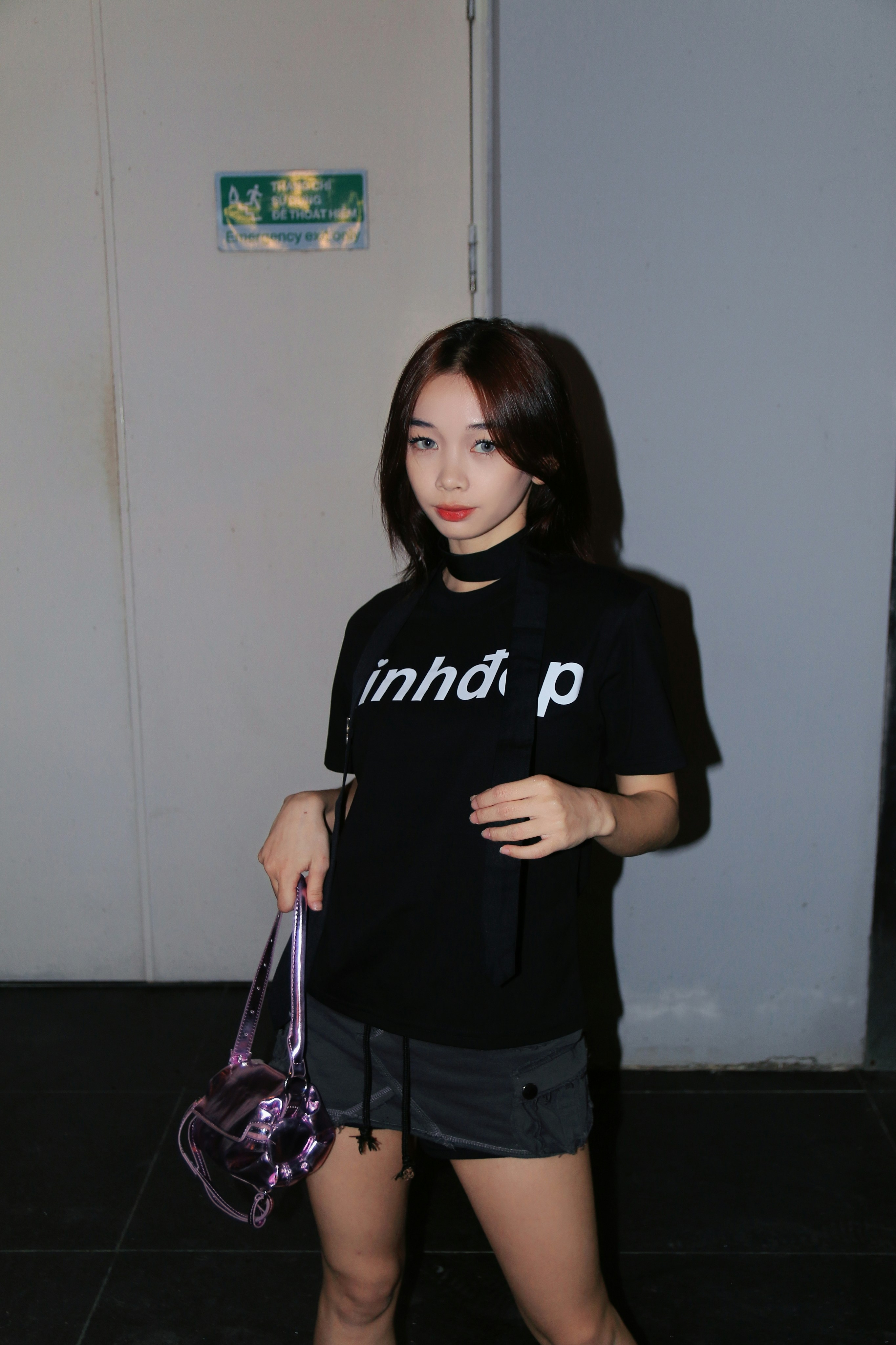 eine junge Frau hält eine Handtasche in der Hand und posiert für ein Foto