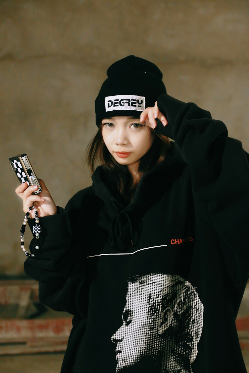 a girl in a black hoodie holding a cell phone