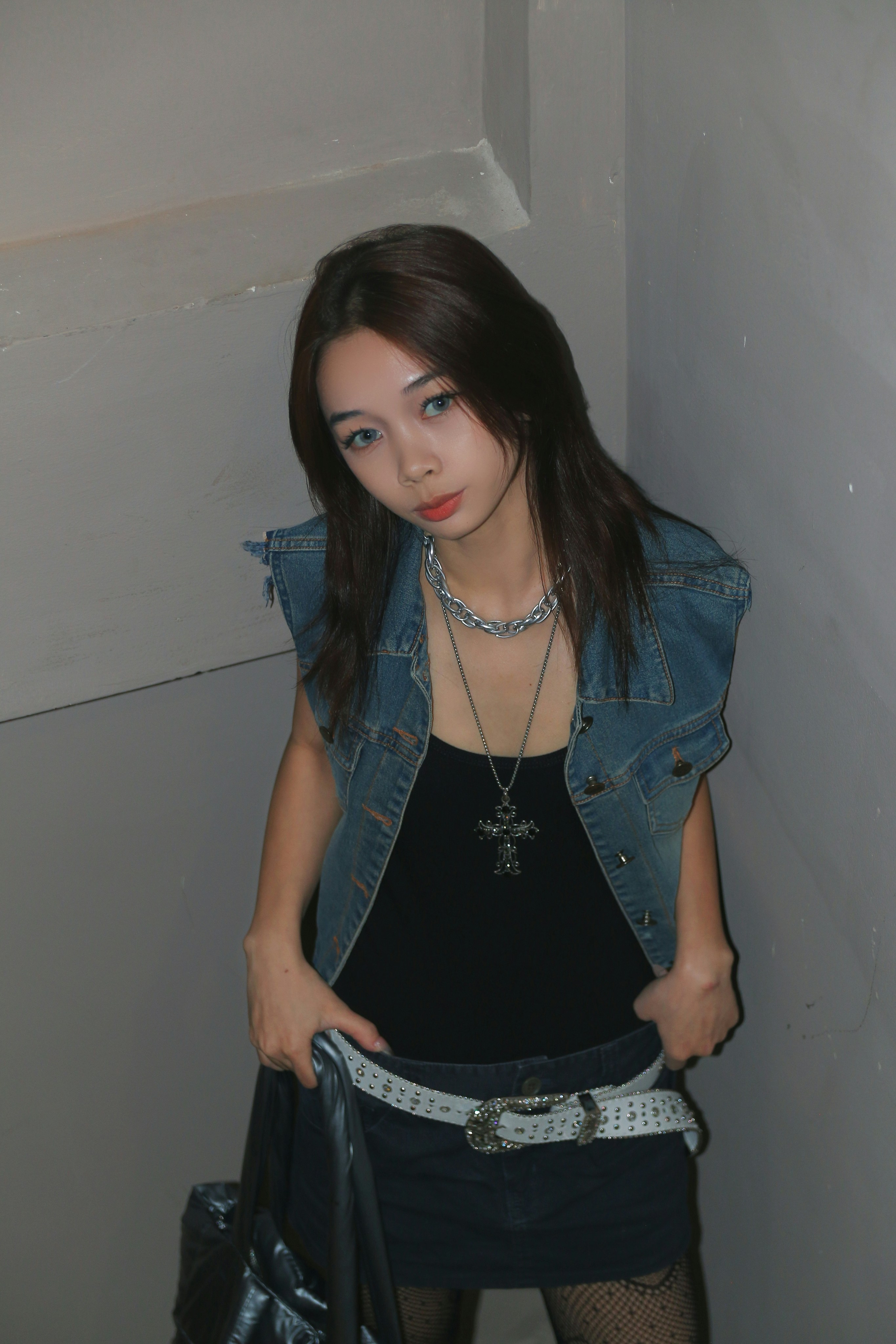 a woman in a black dress and jean jacket holding a black purse
